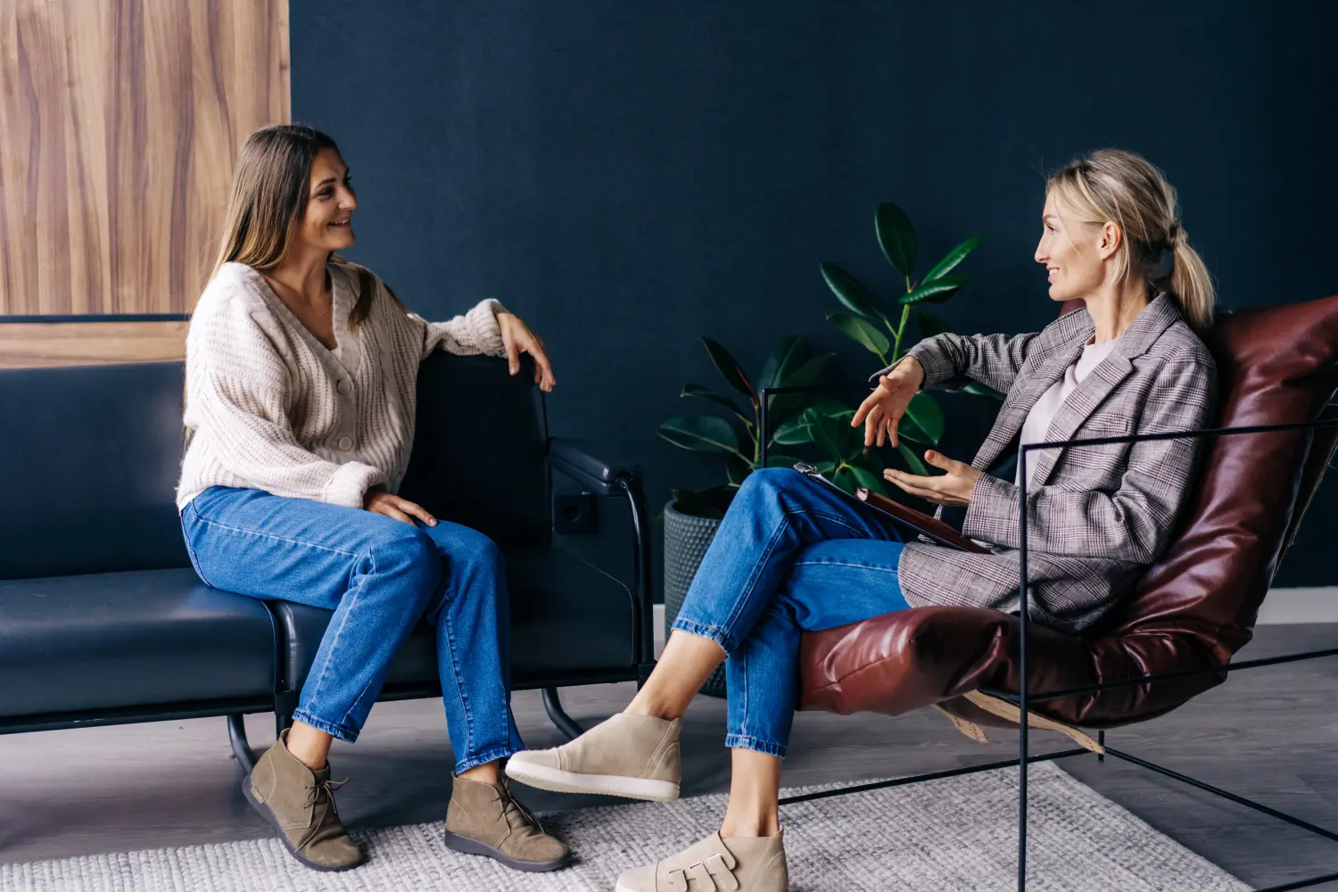 Zwei moderne, stilvolle Frauen sitzen im Büro und besprechen Ideen und die Umsetzung von Plänen. Ein vertrauliches Gespräch zwischen einer Frau und einem beratenden Psychologen.